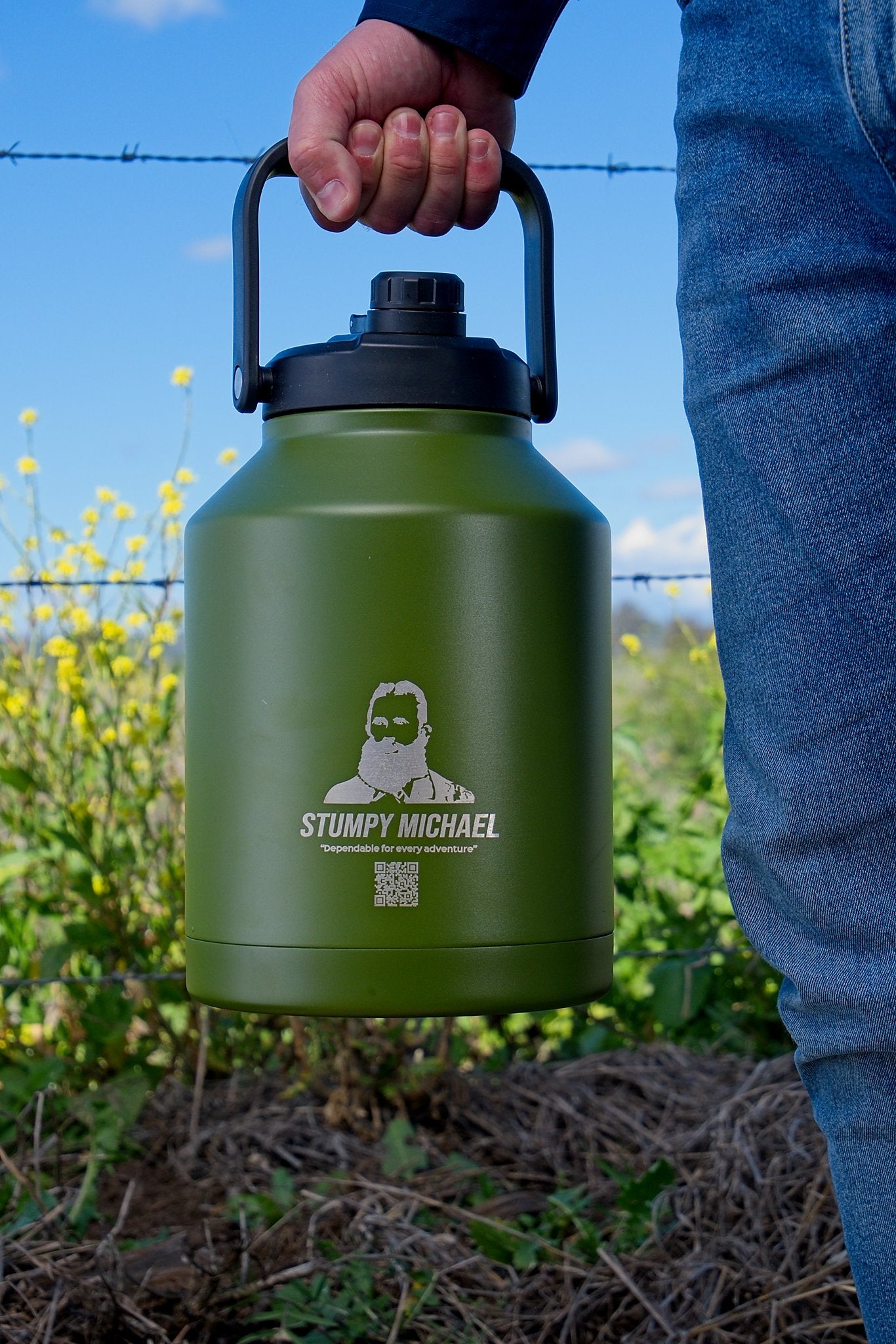 Green water bottle with 'Stumpy Michael' branding held by a person outdoors.