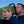 Man drinking from a green thermos in an outdoor setting with a clear sky.