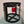 Black metal cage with a red lock on a light blue stool against a beige wall.