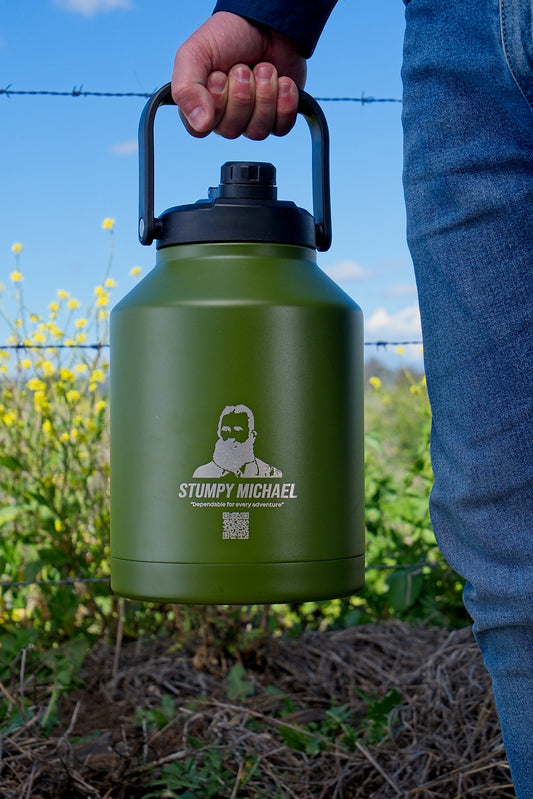 Green water bottle with 'Stumpy Michael' branding held by a person outdoors.