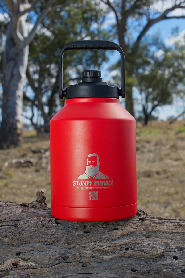 Red Stumpy Michael water bottle on a log with trees in the background