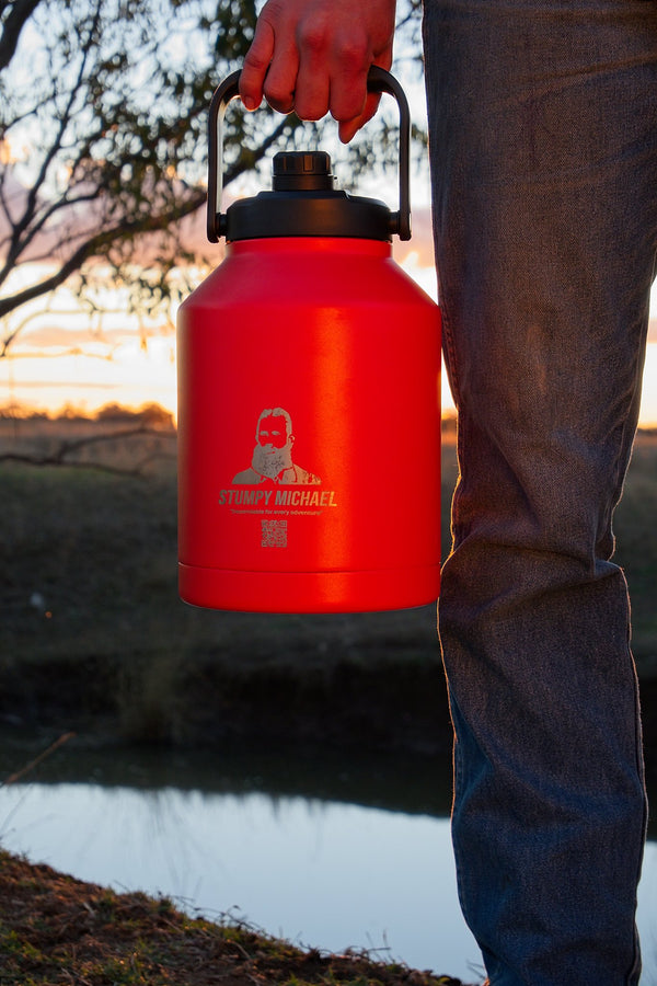 Person holding a red water container with a logo against a natural background